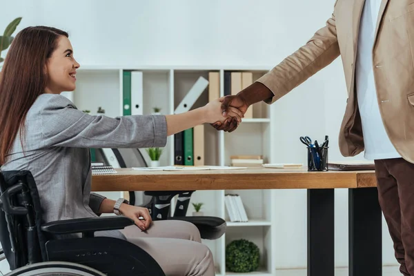 Disabled employee and african american recruiter shaking hands at job interview in office — Stock Photo