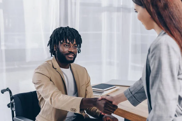 Impiegato afroamericano disabile e reclutatore che si stringono la mano e si guardano a vicenda al colloquio di lavoro — Foto stock