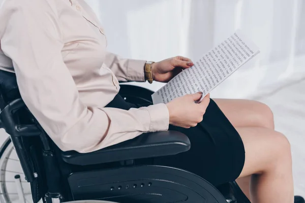 Vista recortada del reclutador discapacitado con papeles en silla de ruedas en la oficina - foto de stock