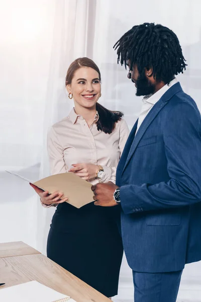 Datore di lavoro con la cartella aperta sorridente, indicando la cartella aperta e guardando il reclutatore afro-americano in carica — Foto stock