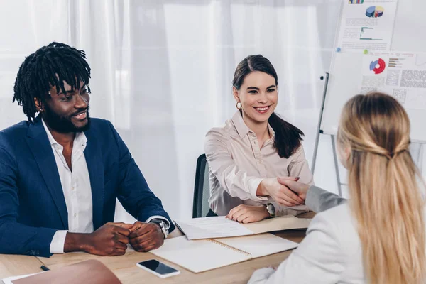 Enfoque selectivo del empleador afroamericano y reclutador estrechando la mano con el empleado en la entrevista de trabajo en la oficina - foto de stock