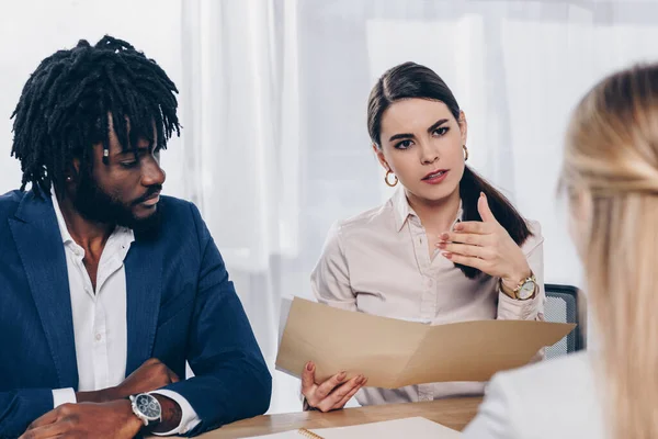 Foco seletivo de recrutadores multiétnicos que conduzem a entrevista de emprego com empregado à mesa no escritório — Fotografia de Stock