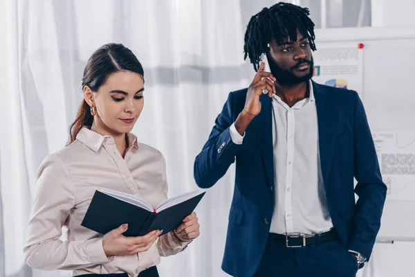 African american employer talking on smartphone and recruiter with notebook in office — Stock Photo