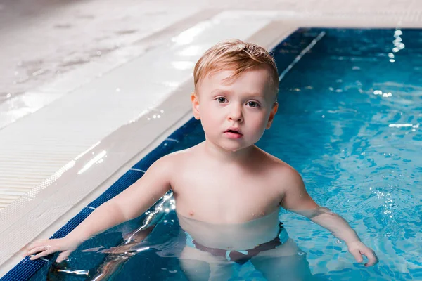 Cute toddler kid looking at camera in swimming pool — Stock Photo
