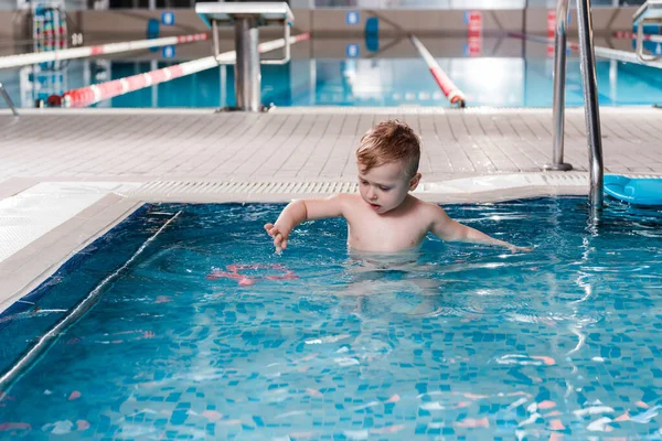 Niedliche Kleinkind Blick auf Gummispielzeug im Schwimmbad — Stockfoto