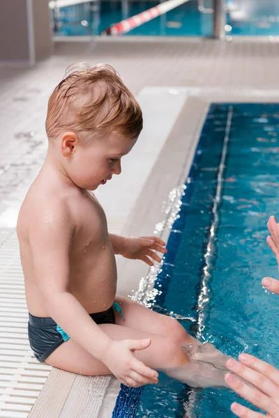 Vista recortada de entrenador de natación cerca de niño lindo en la piscina - foto de stock