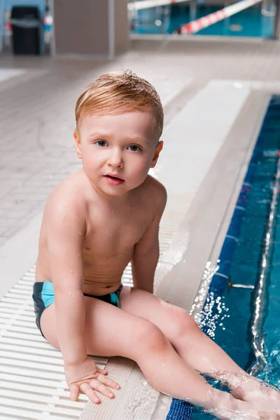 Adorable toddler boy sitting near swimming pool — Stock Photo