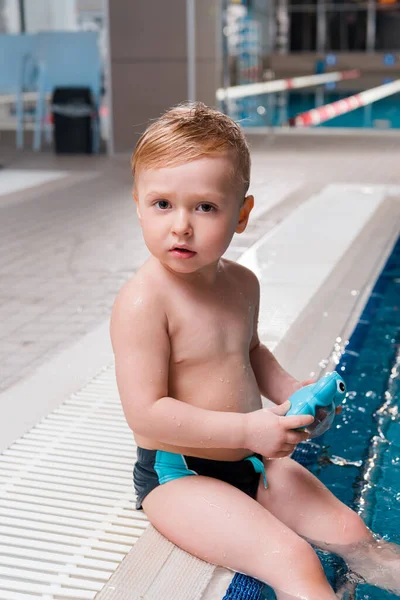 Entzückende Kleinkind Junge sitzt in der Nähe von Schwimmbad mit Gummispielzeug — Stockfoto