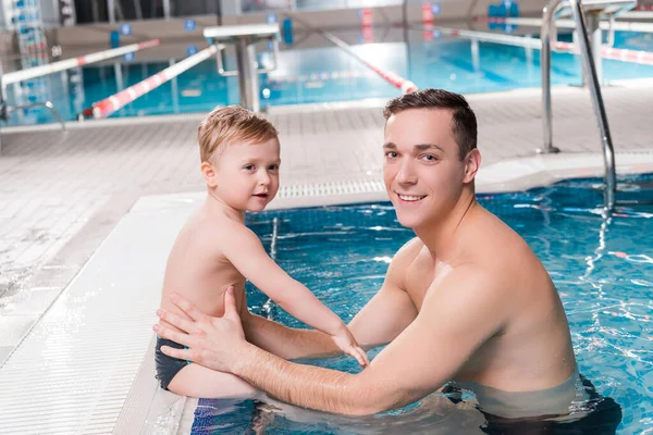 Entrenador de natación feliz y niño pequeño cerca de la piscina - foto de stock