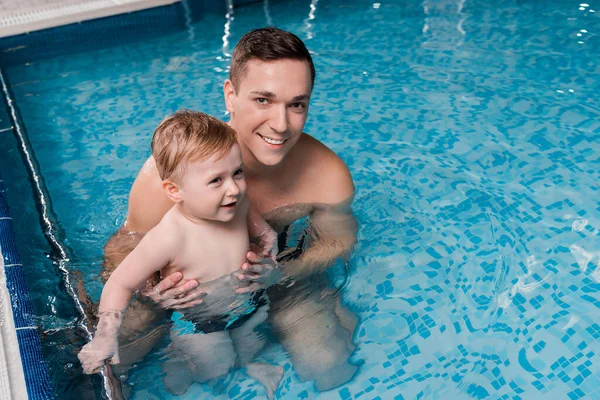 Happy swim coach teaching toddler kid in swimming pool — Stock Photo