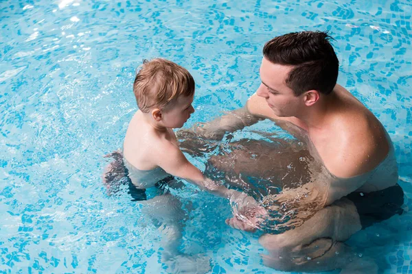 Vue aérienne de l'entraîneur de natation heureux enseignant tout-petit enfant dans la piscine — Photo de stock