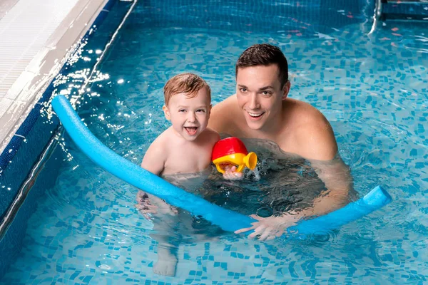 Bonito natação treinador sorrindo com criança menino na piscina — Fotografia de Stock