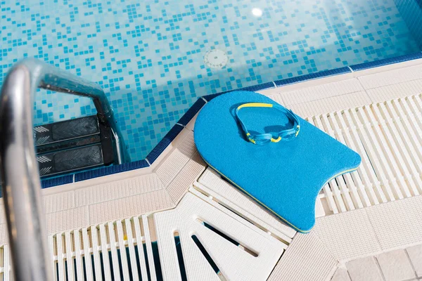 Vista superior de óculos de natação na prancha de flutter perto da piscina — Fotografia de Stock
