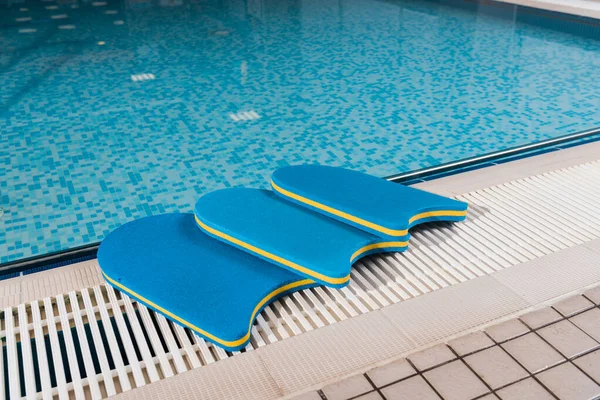 Planches de flottement bleu près de la piscine dans le centre sportif — Photo de stock