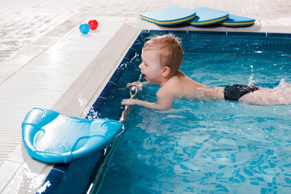 Felice bambino ragazzo nuotare vicino flutter tavole in piscina — Foto stock