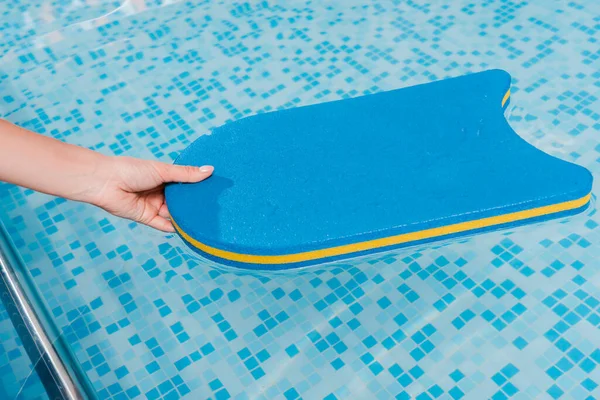 Cropped view of woman touching flutter board in swimming pool — Stock Photo