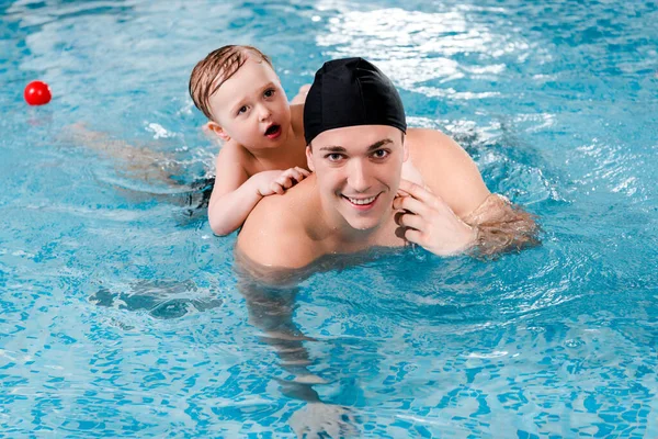 Happy swim coach and toddler boy training in swimming pool — Stock Photo
