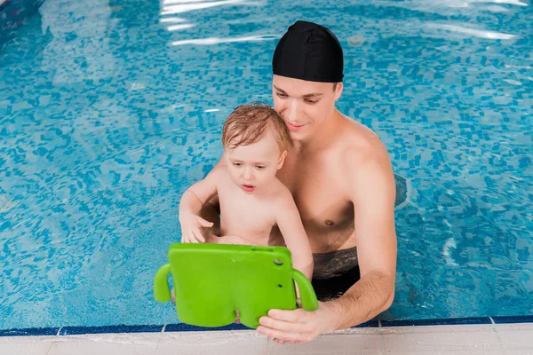 Bello nuotare allenatore e bambino ragazzo nuoto e guardando tablet digitale — Foto stock