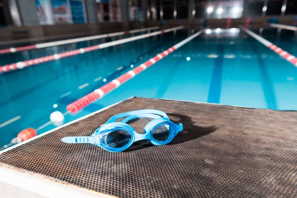Goggles near swimming pool with blue water — Stock Photo