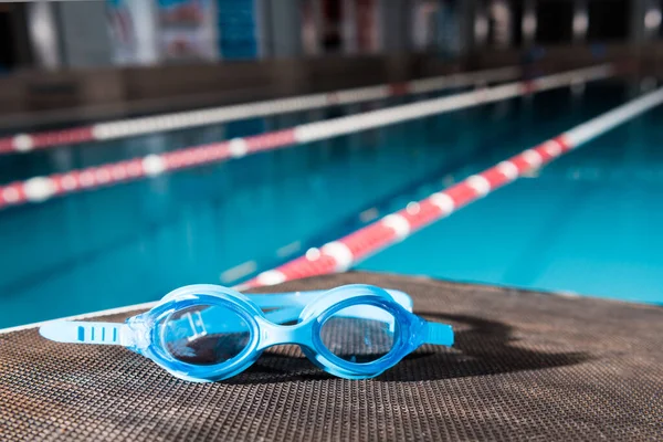 Blue goggles near swimming pool in sports center — Stock Photo
