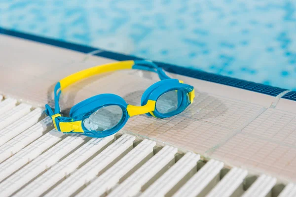 Gafas cerca de la piscina con agua azul - foto de stock