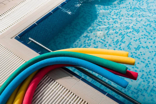 Top view of colorful pool noodles near swimming pool — Stock Photo