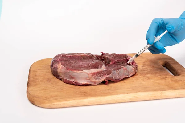 Vista recortada del médico con la jeringa haciendo inyección hormonal en carne cruda en la tabla de cortar aislado en blanco - foto de stock