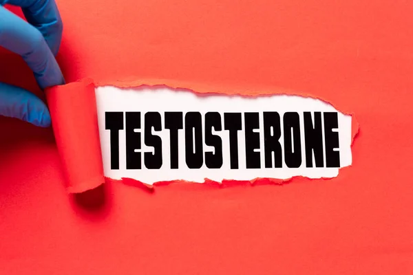 Vista ritagliata del medico che strappa carta rossa con scritte di testosterone sulla superficie bianca — Foto stock