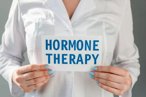 Vue agrandie d'un médecin tenant une carte avec lettrage hormonal isolé sur gris — Photo de stock