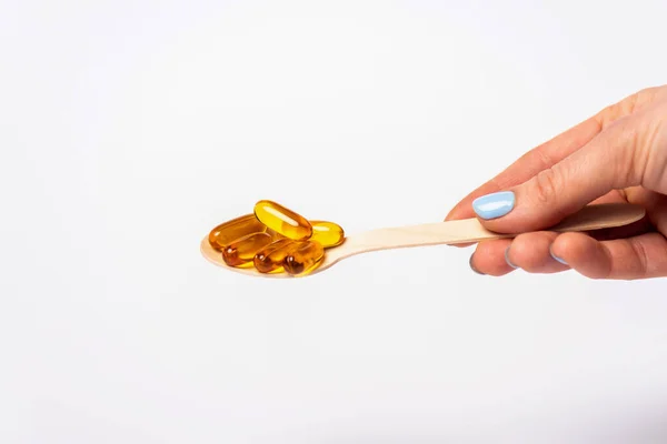 Cropped view of woman holding wooden spoon with pills of omega 3 isolated on white — Stock Photo