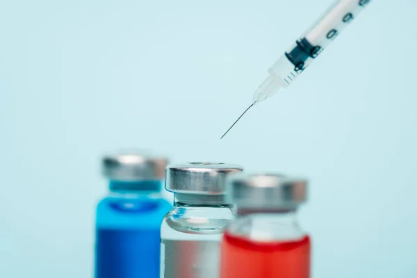Concentration sélective de pots de médicaments hormonaux et de seringues isolés sur du bleu — Photo de stock
