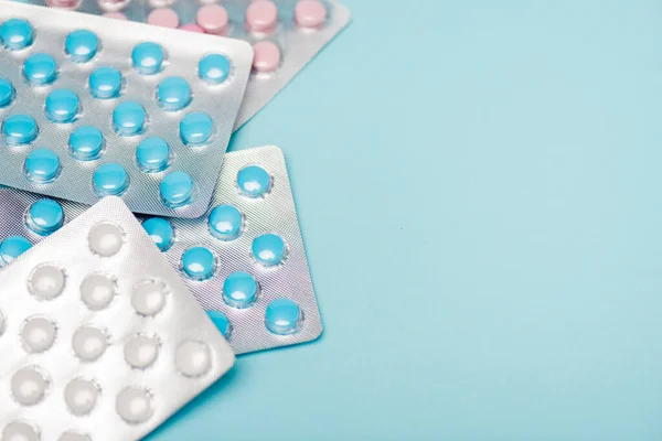 Vue rapprochée des pilules hormonales sous plaquettes thermoformées sur la surface bleue — Photo de stock
