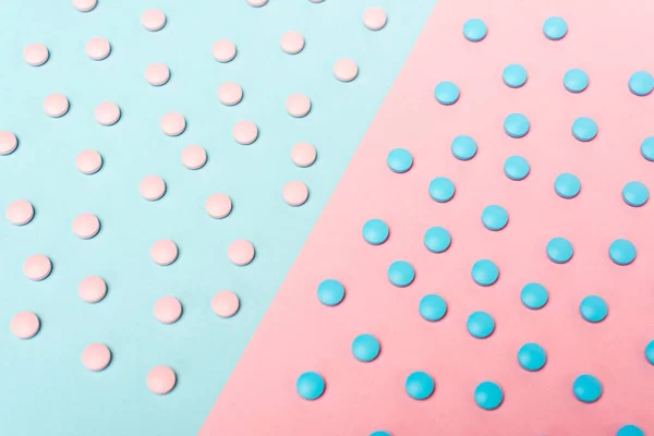 Vista de ángulo alto de las píldoras hormonales en la superficie azul y rosa - foto de stock