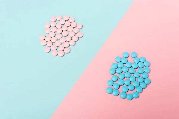 Vista de ángulo alto de píldoras hormonales sobre fondo azul y rosa - foto de stock