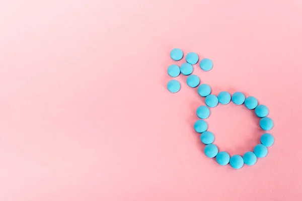 Вид сверху мужского знака из гормональных таблеток на розовом фоне — стоковое фото