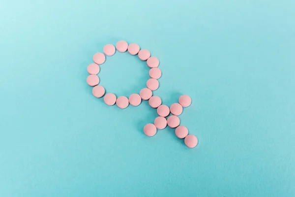 Vista de ángulo alto de signo femenino de píldoras hormonales sobre fondo azul - foto de stock