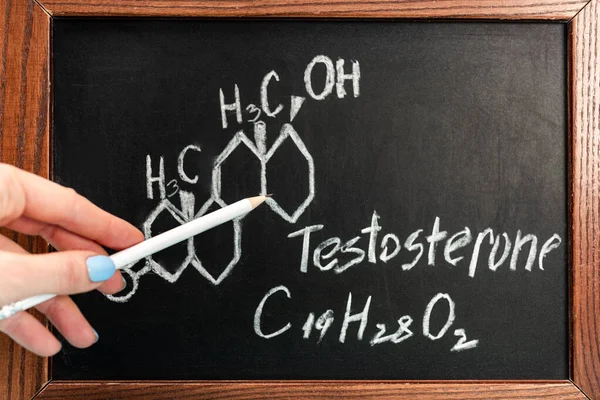 Cropped view of woman holding pencil near blackboard with testosterone formula — Stock Photo