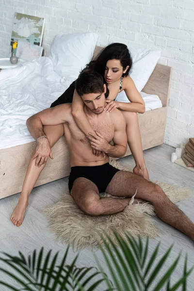 Чоловік на хутрі біля жінки на ліжку обіймається в спальні — стокове фото