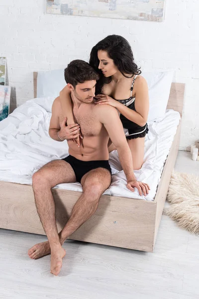 Visão de alto ângulo de namorada atraente abraçando namorado na cama no quarto — Fotografia de Stock