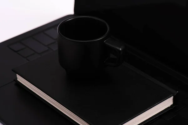 Notebook preto e copo no teclado do laptop isolado no branco — Fotografia de Stock