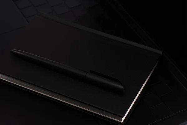 Close up of black notebook and pen on laptop keyboard — Stock Photo