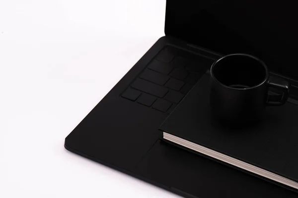 Notebook and cup on black laptop isolated on white — Stock Photo