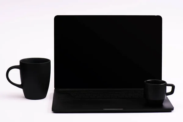 Cups of coffee and black laptop with blank screen on white — Stock Photo