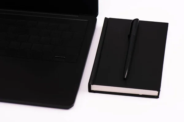 Notebook e caneta perto de laptop preto isolado em branco — Fotografia de Stock