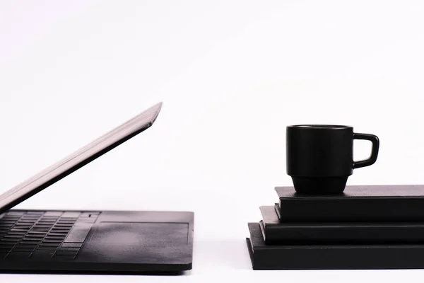 Tasse auf Notizbüchern neben schwarzem Laptop auf weißem — Stockfoto