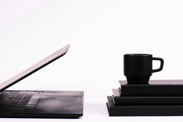 Tasse sur carnets près ordinateur portable noir sur blanc — Photo de stock
