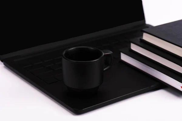 Carnets et tasse près ordinateur portable noir et moderne isolé sur blanc — Photo de stock