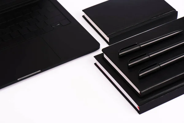 Ручки і блокноти біля сучасного ноутбука ізольовані на білому — стокове фото