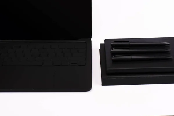 Ручки и ноутбуки рядом с современным ноутбуком с чистым экраном изолированы на белом — стоковое фото