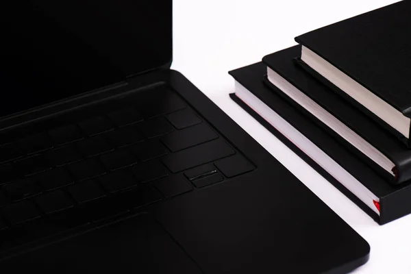 Portátil negro con pantalla en blanco cerca de cuadernos aislados en blanco - foto de stock